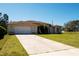 Charming single-story home featuring an attached two-car garage and a well-maintained front yard with green grass at 10400 Golden Ave, Weeki Wachee, FL 34613