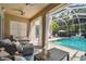 Covered patio with comfortable seating overlooks the screened pool and tropical landscaping at 10608 Gretna Green Dr, Tampa, FL 33626