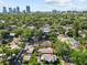 Aerial view showcasing the tree-lined neighborhood with a city skyline in the distance at 1115 Crescent Lake N Dr, St Petersburg, FL 33701