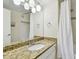 Well-lit bathroom features a large granite counter, an oval sink, and a shower with a curtain at 115 112Th Ne Ave # 1027, St Petersburg, FL 33716