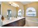 Bright bathroom featuring double vanity, garden tub, and a window with a lake view at 12170 Lake Allen Dr, Largo, FL 33773
