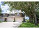 Townhouse exterior featuring a two-car garage, well-maintained lawn, and mature trees providing shade at 12170 Lake Allen Dr, Largo, FL 33773