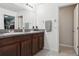 Bathroom featuring dual sinks with dark wood cabinets, granite countertops and an access door to the closet at 12618 Sandpine Reserve Pl, Gibsonton, FL 33534
