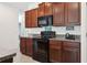 Kitchen showcasing granite countertops, wooden cabinetry, and modern black appliances at 12618 Sandpine Reserve Pl, Gibsonton, FL 33534