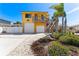 Charming yellow two-story home with lush landscaping, palm trees, and a two-car garage at 13514 Garris Dr, Hudson, FL 34667