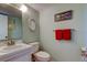 Compact bathroom featuring a vanity, toilet, decorative mirrors, and vibrant red towels at 14130 Rosemary Ln # 3312, Largo, FL 33774