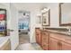 Bathroom showcasing dual sinks, wood cabinets, and an open doorway leading into the primary bedroom at 15723 Starling Water Dr, Lithia, FL 33547
