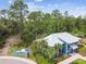 Aerial view of a blue and white clubhouse with a playground, lush landscaping, and a metal roof at 16822 Balance Cv, Land O Lakes, FL 34638