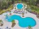 Aerial view of a community pool with lounge chairs, palm trees, and a water park area at 16822 Balance Cv, Land O Lakes, FL 34638