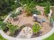 Aerial view of a playground with a wooden playset, a fire pit, chairs, and a paved walkway at 16822 Balance Cv, Land O Lakes, FL 34638