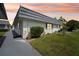 Attractive white single-story home featuring a well-manicured lawn and mature landscaping during sunset at 205 Andover N Pl # 110, Sun City Center, FL 33573