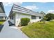 Attractive white single-story home featuring a well-manicured lawn and mature landscaping at 205 Andover N Pl # 110, Sun City Center, FL 33573