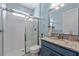Bright bathroom with white tile shower, blue vanity and granite counter tops at 2121 Secret Cv, Odessa, FL 33556