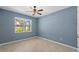 This cozy bedroom offers natural light from the window overlooking the backyard and features a ceiling fan at 2121 Secret Cv, Odessa, FL 33556