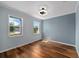 Bedroom with hardwood floors, blue walls, white trim, ceiling fan, and two windows at 2121 Secret Cv, Odessa, FL 33556