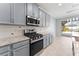 Features a spacious kitchen with gray cabinets, stainless appliances, granite countertops, and views of the backyard at 2121 Secret Cv, Odessa, FL 33556