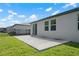 A view of the backyard featuring a concrete patio, grassy area, and a black metal fence at 3087 Forrest Plum Ct, Zephyrhills, FL 33540