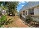 A tranquil outdoor walkway shows the side of a bright home with several windows in a lush, tropical setting at 4227 Glissade Dr, New Port Richey, FL 34652