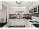 Clean kitchen with white cabinets, white appliances and dark countertops, plus view to outdoor living area at 4227 Glissade Dr, New Port Richey, FL 34652
