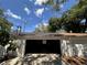 View of the garage with an open garage door, shade from trees, and overhead power lines at 4624 W North B St, Tampa, FL 33609