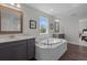 Dual-sink bathroom featuring tile floor, separate bathtub, and framed mirrors above each sink at 4777 Ballantrae Blvd, Land O Lakes, FL 34638