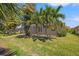 Private backyard with mature palm trees, a screened-in patio, and ample green space at 8078 Pine Crest St, Seminole, FL 33777