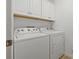 The laundry room has a side by side washer and dryer along with white cabinets for storage at 8078 Pine Crest St, Seminole, FL 33777