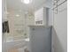 Compact bathroom featuring a shower-tub combo with glass doors, cabinet, and a well-lit vanity area at 870 Virginia St # 109, Dunedin, FL 34698
