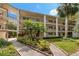 A view of the condo's exterior, showing multiple levels, black metal balconies, and lush, tropical landscaping at 870 Virginia St # 109, Dunedin, FL 34698