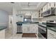 Updated condo kitchen showcasing stainless steel appliances, a convenient breakfast bar, and a view into living area at 870 Virginia St # 109, Dunedin, FL 34698