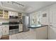 Condo kitchen featuring white cabinetry, stainless steel appliances, and a pass-through to the entryway at 870 Virginia St # 109, Dunedin, FL 34698