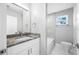 Bathroom with granite countertops, white cabinets, and neutral tiled shower and tub at 1030 11Th S Ave, St Petersburg, FL 33705