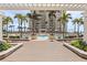 Luxury pool area featuring pergola, multiple seating areas, lush tropical landscaping, and a glimpse of the ocean at 11 Baymont St # 1109, Clearwater Beach, FL 33767