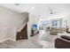 Open-concept living space with wood-look tile, staircase, plush sectional and a ceiling fan at 11521 Crowned Sparrow Ln, Tampa, FL 33626