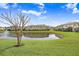 Beautiful view of the community pond reflecting the townhomes under a sunny, cloudy sky at 11521 Crowned Sparrow Ln, Tampa, FL 33626