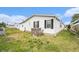 Exterior view of a white home with well-kept lawn and functional AC unit at 12501 Ulmerton Rd # 133, Largo, FL 33774