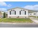 Charming single-story home featuring white siding, black shutters, decorative window trim, and covered parking at 12501 Ulmerton Rd # 133, Largo, FL 33774