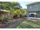 View of a landscaped backyard featuring a lush lawn and tropical trees surrounding the property at 126 Orangewood Dr, Dunedin, FL 34698