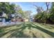 Expansive backyard with a sparkling pool, manicured lawn, mature trees, storage shed and lush landscaping at 126 Orangewood Dr, Dunedin, FL 34698