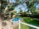 Lush backyard with mature trees, a swimming pool, green lawn, and a shed, perfect for outdoor living at 126 Orangewood Dr, Dunedin, FL 34698