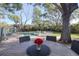 Backyard area with outdoor table and chairs, and a swimming pool under mature trees at 126 Orangewood Dr, Dunedin, FL 34698
