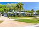 Charming home with well-manicured lawn, lush landscaping, palm trees, and a quaint outdoor seating area at 126 Orangewood Dr, Dunedin, FL 34698