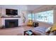 Living room features a fireplace, television, light hardwood floors, gray couch and a view through bay windows at 126 Orangewood Dr, Dunedin, FL 34698
