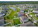 Aerial shot of the property with a spacious backyard, wooden playset, and white fence, set within a community near a pond at 13113 Rain Lily Dr, Riverview, FL 33579
