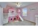 Bright bedroom featuring a castle-themed bunk bed with a slide and steps and pink walls at 13113 Rain Lily Dr, Riverview, FL 33579