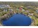 Expansive aerial shot of a lakefront property with a private dock, nestled among lush trees and tranquil waters at 16119 Carencia Ln, Odessa, FL 33556