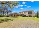 Large backyard showcasing the house, screened-in patio, and a well-manicured lawn with mature trees at 16119 Carencia Ln, Odessa, FL 33556