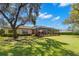 Spacious backyard features lush grass, mature trees, and a screened-in patio, perfect for outdoor living at 16119 Carencia Ln, Odessa, FL 33556