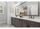 Modern bathroom featuring double sinks, marble countertop, gray cabinets, and decorative vases and artwork at 16119 Carencia Ln, Odessa, FL 33556