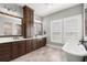 Bathroom with dual sinks, soaking tub, wood cabinets, large mirrors, and tile floor at 16119 Carencia Ln, Odessa, FL 33556